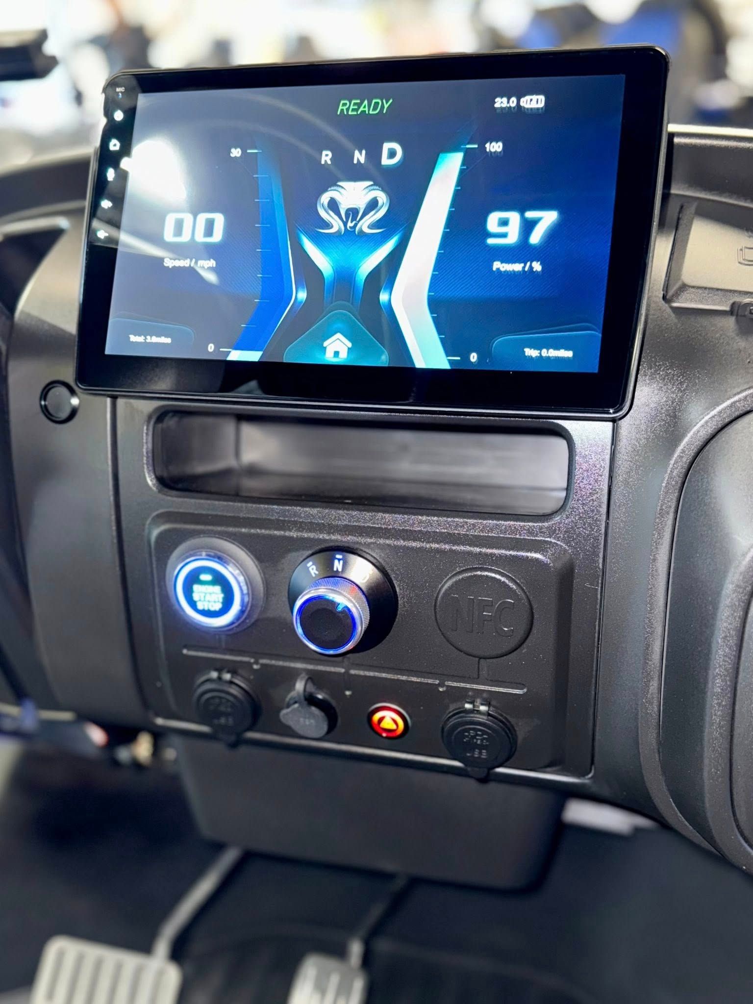 Dashboard with large screen displaying vehicle info, and knobs and buttons below.