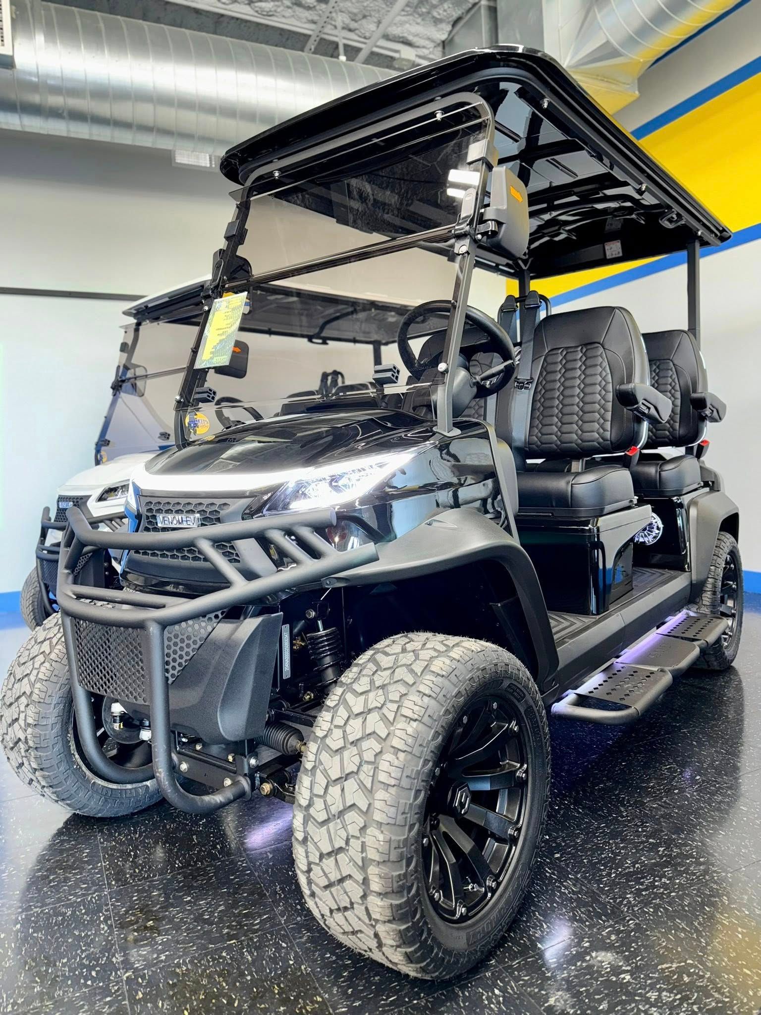 Black golf cart with lifted suspension, rugged tires, and black accessories, indoors.