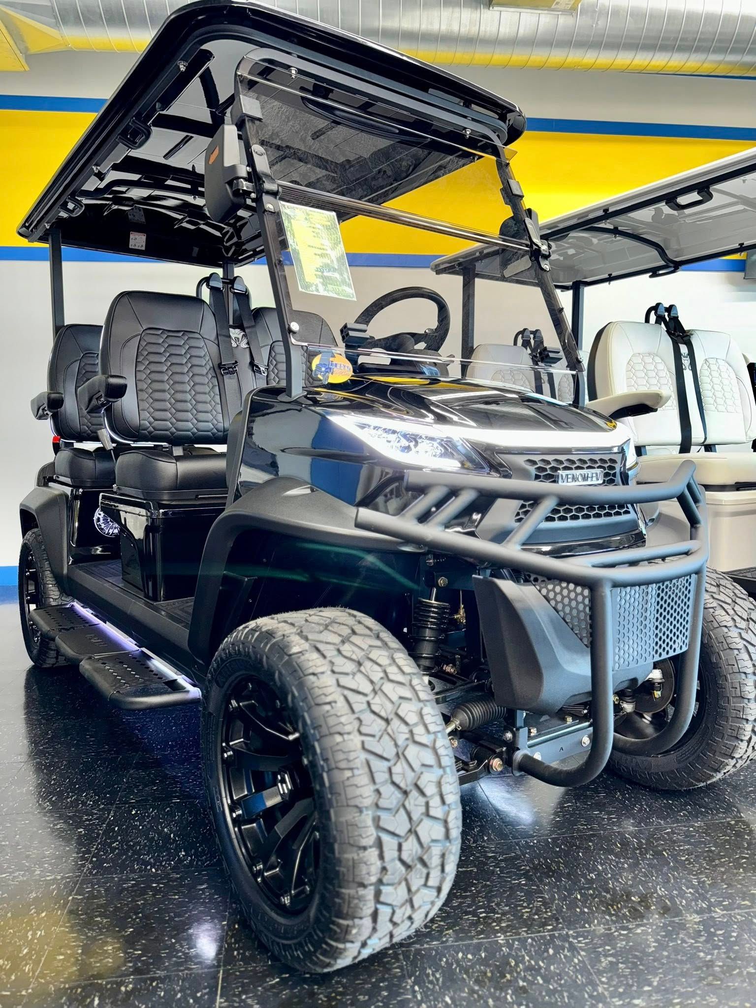 Black golf cart with off-road tires, a front brush guard, and a canopy, indoors.