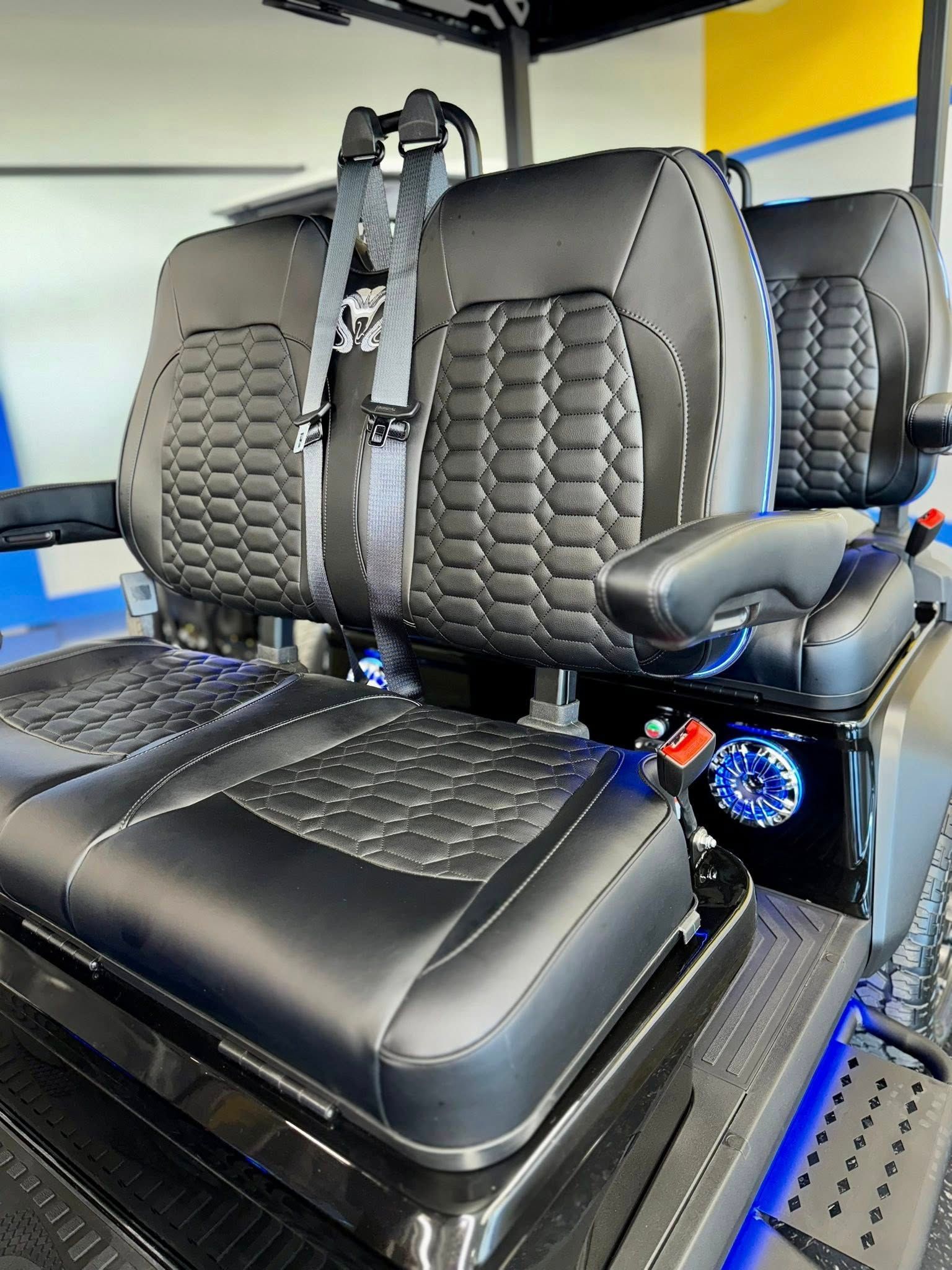 Black golf cart seats with a quilted design and gray seatbelts.