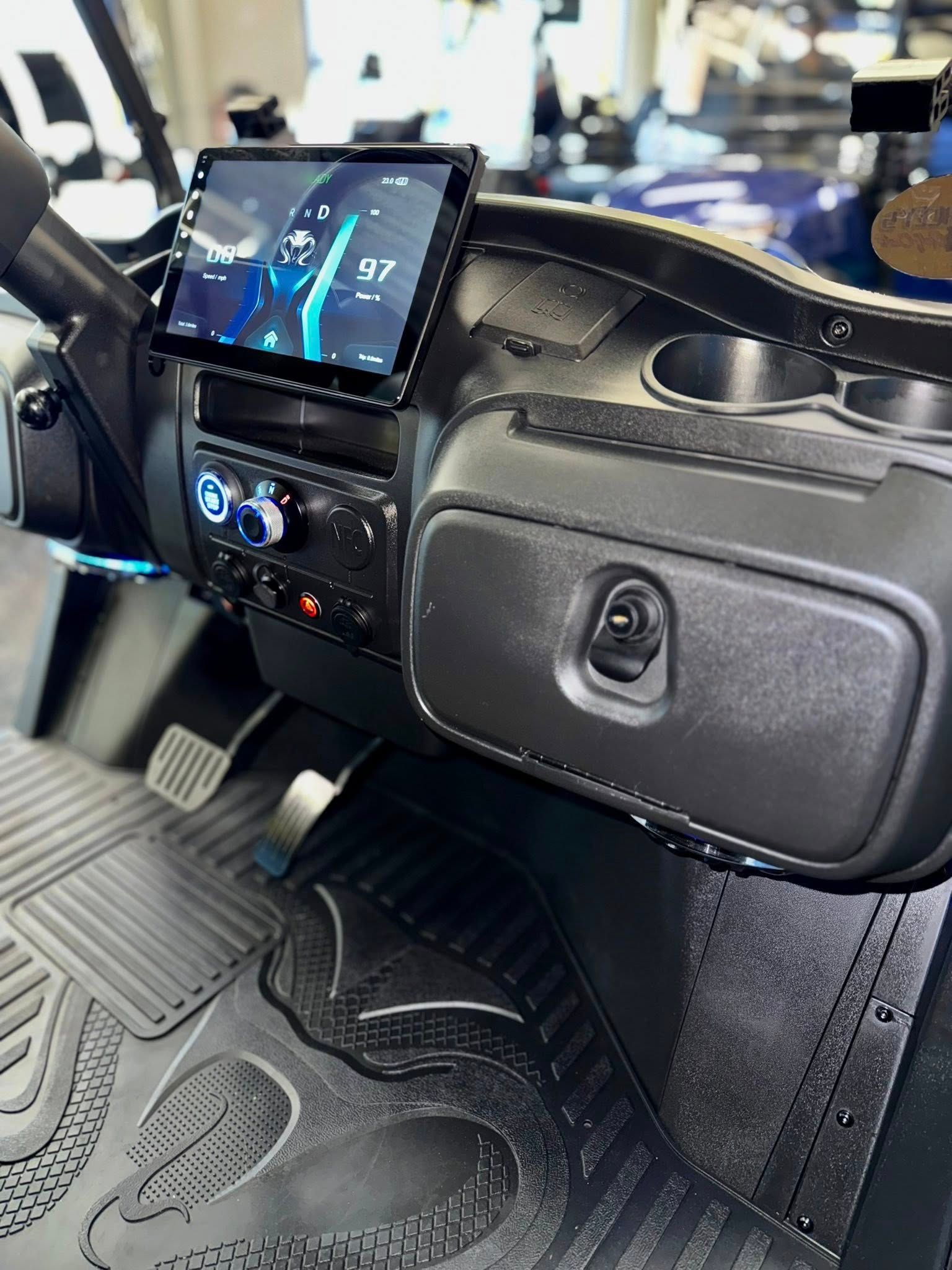 Golf cart dashboard with a digital display, stereo, storage, and a black textured mat.