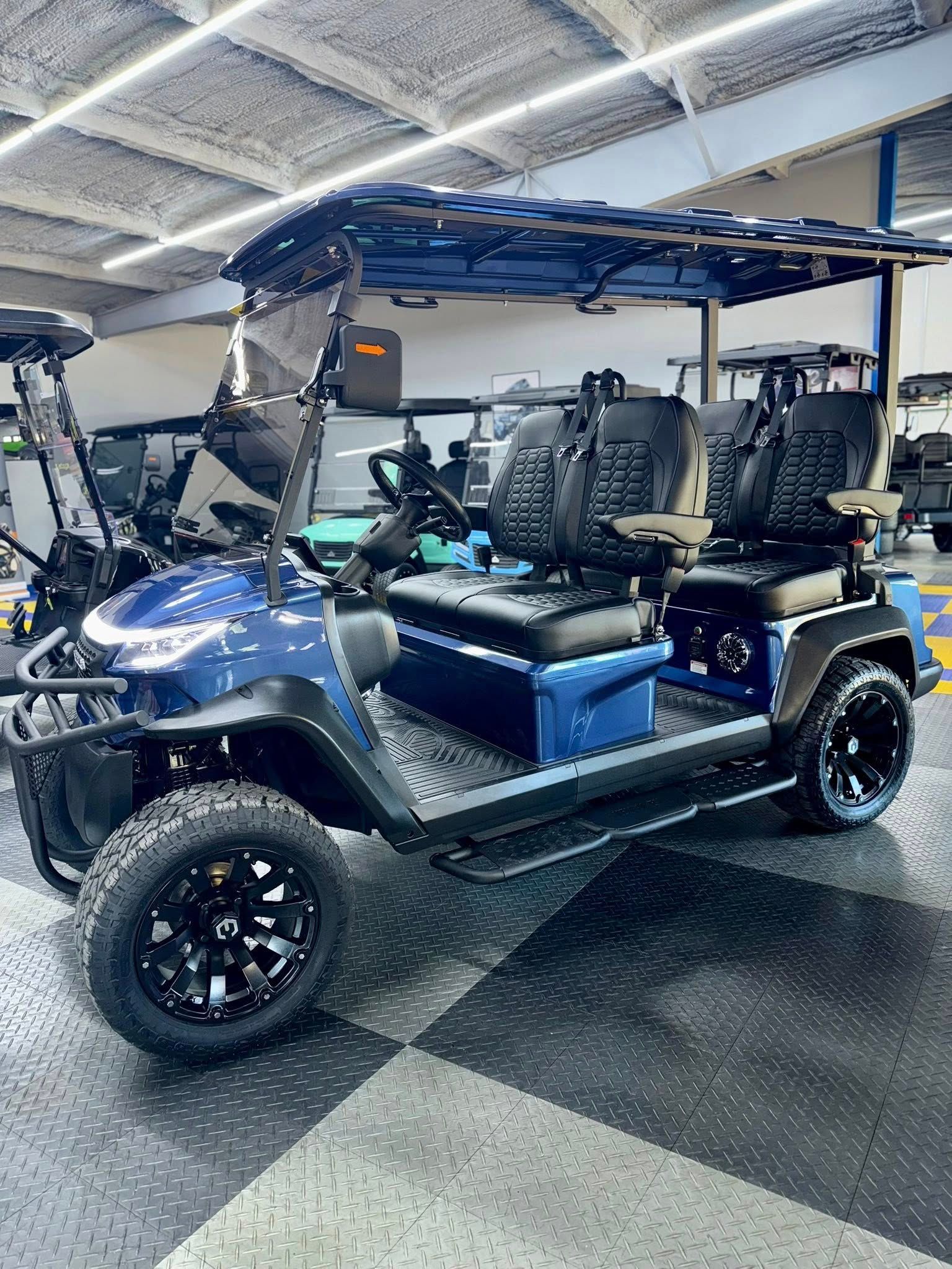 Blue golf cart with black wheels and seats, parked inside a building.