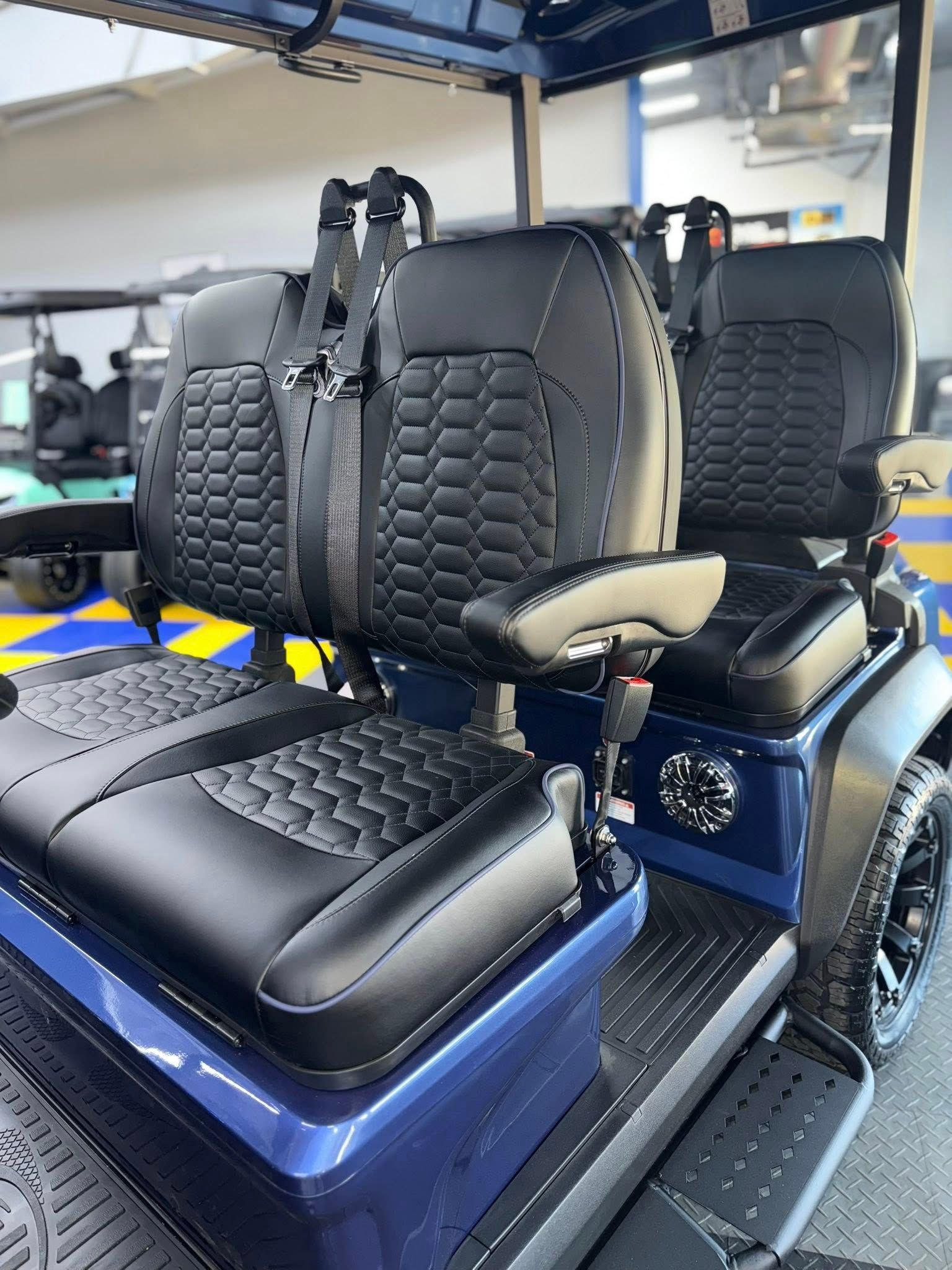 Blue and black golf cart seats with safety belts; close-up view.