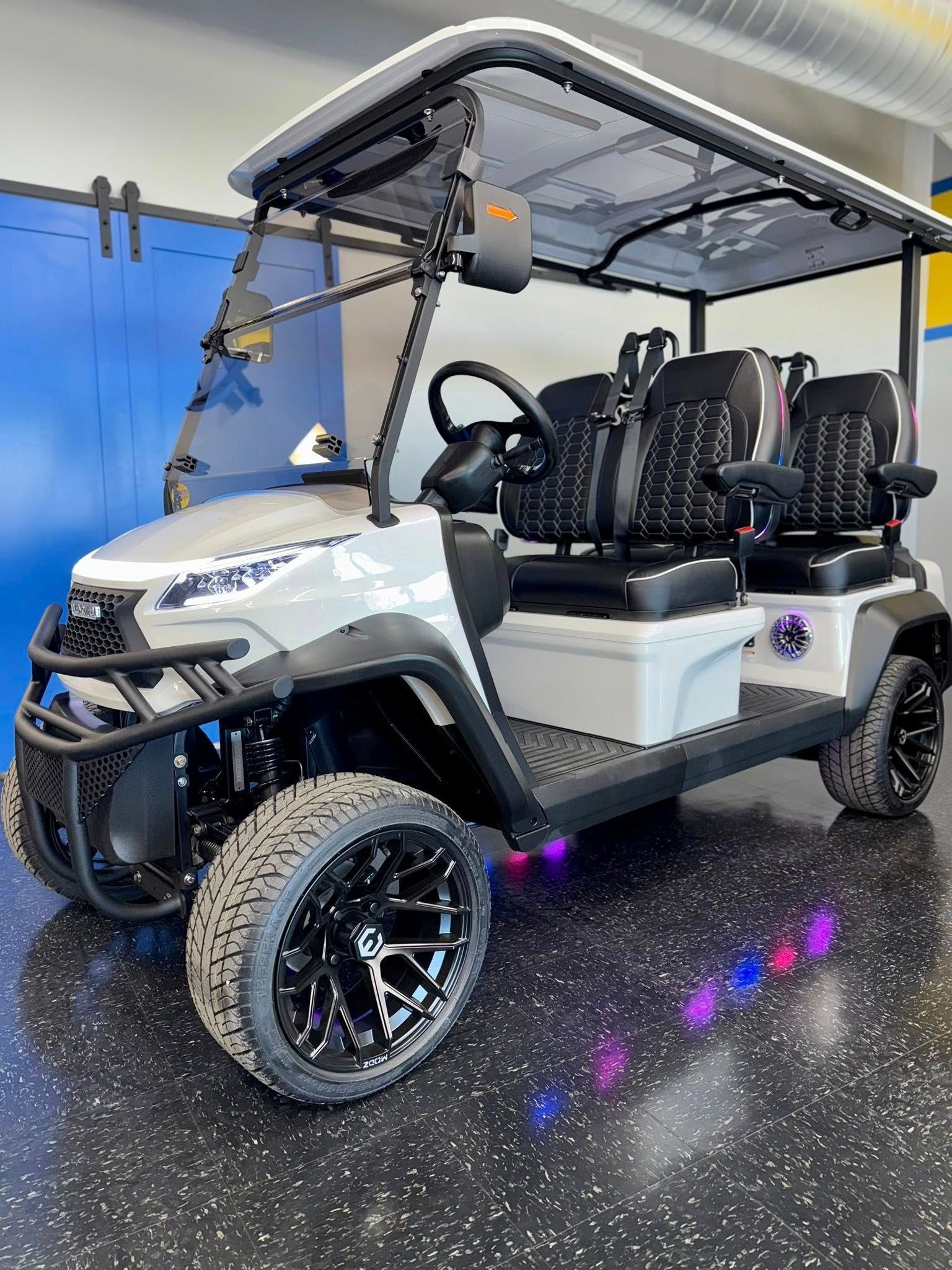 Gray golf cart with black accents, custom wheels, and LED lights, indoors.