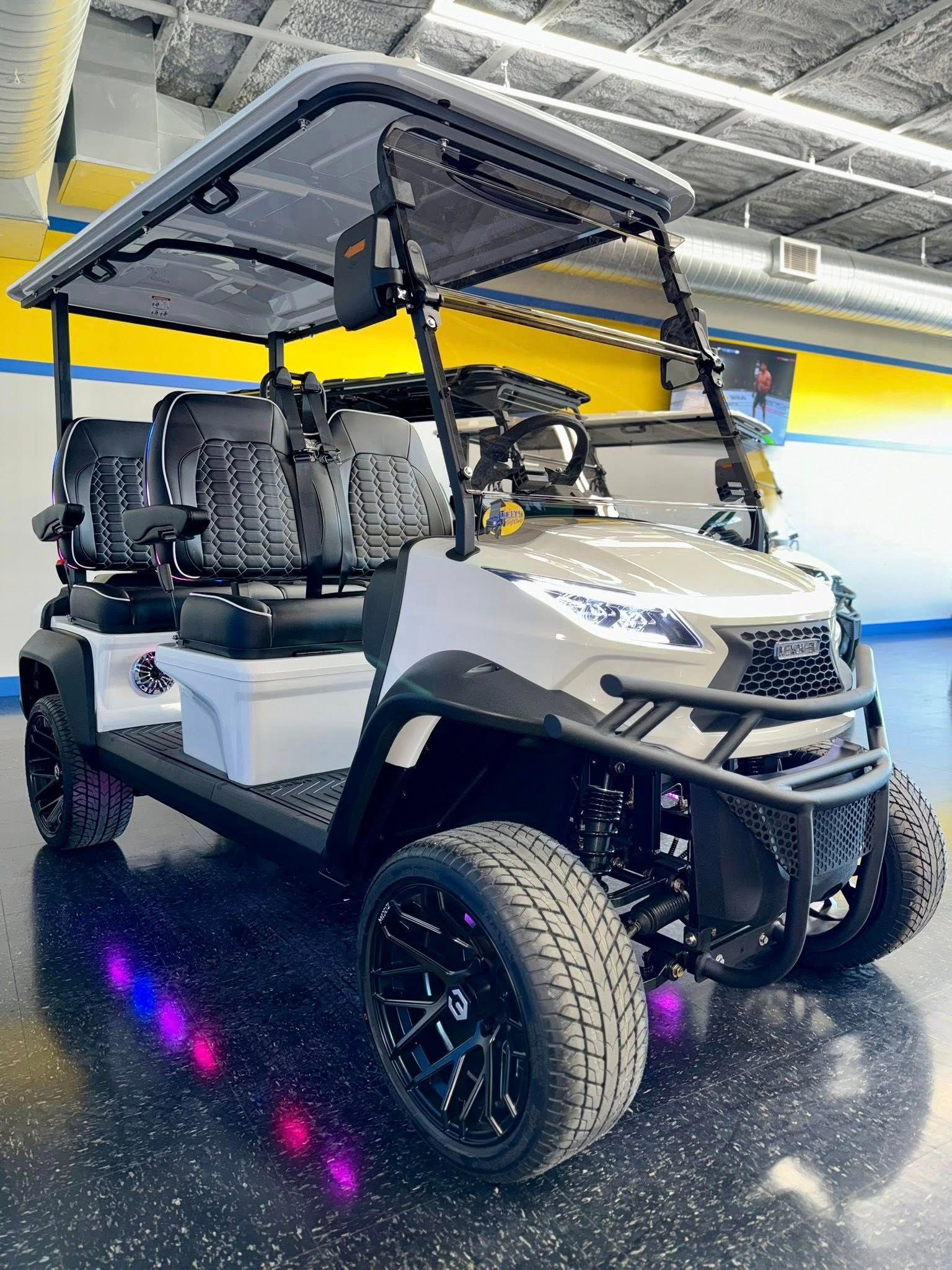 White golf cart with black accents, black wheels, and a gray roof, indoors.
