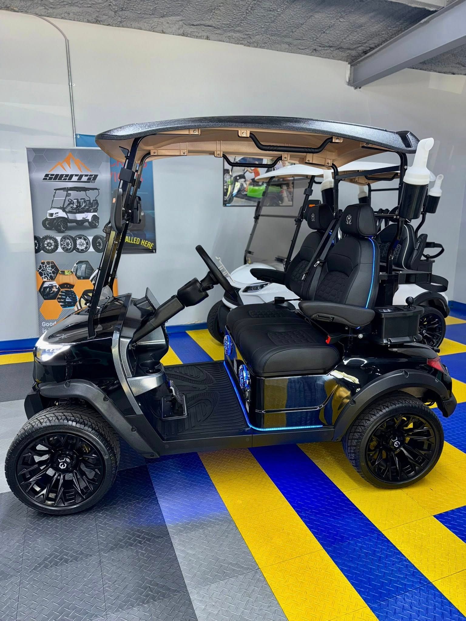 Black, customized golf cart with black wheels and seats parked in a garage with a checkered floor.
