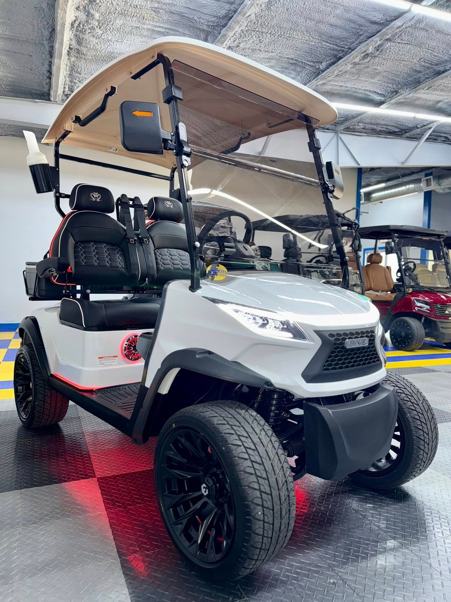 White golf cart with black accents and large tires, parked indoors.