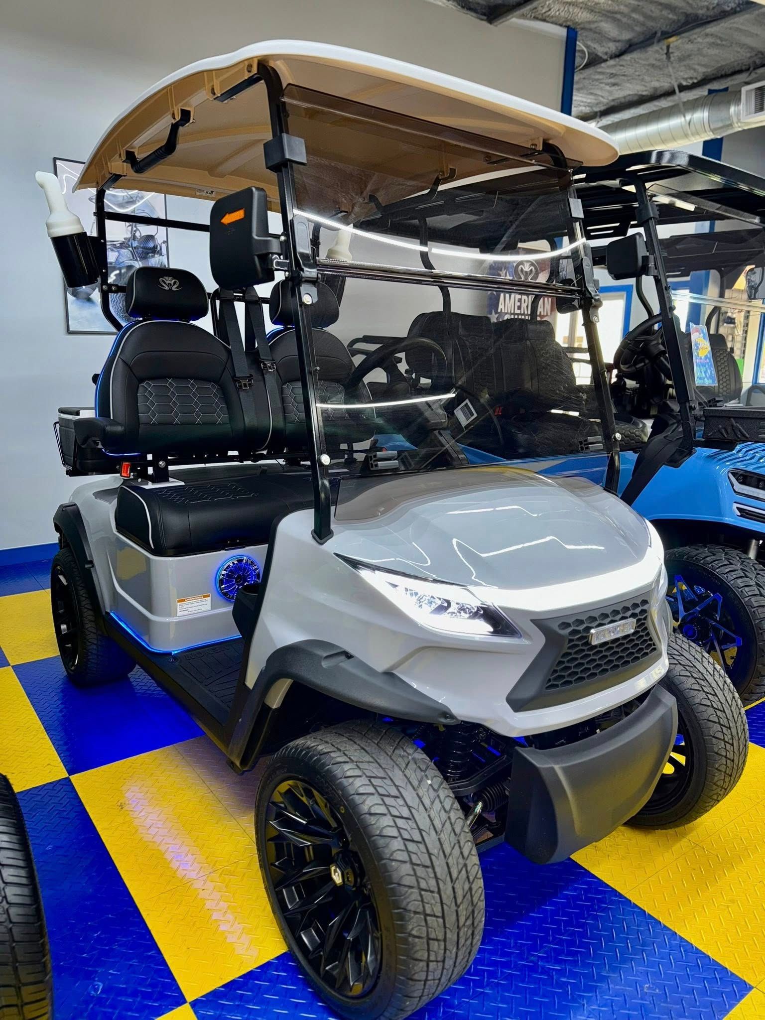Gray and black golf cart with black wheels, on blue and yellow checkered floor.