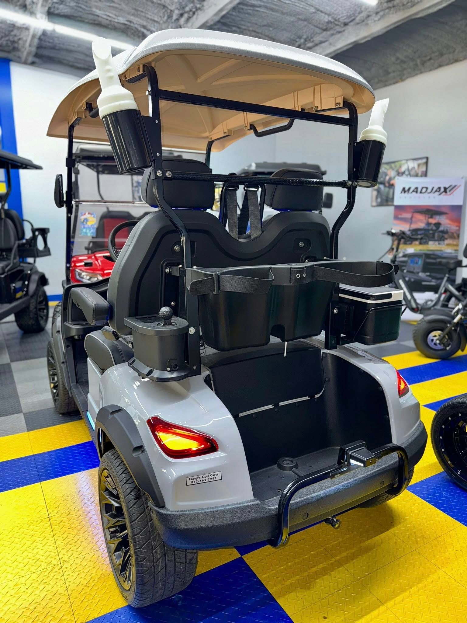 Gray and black golf cart with off-road tires, accessories, and a beige roof.