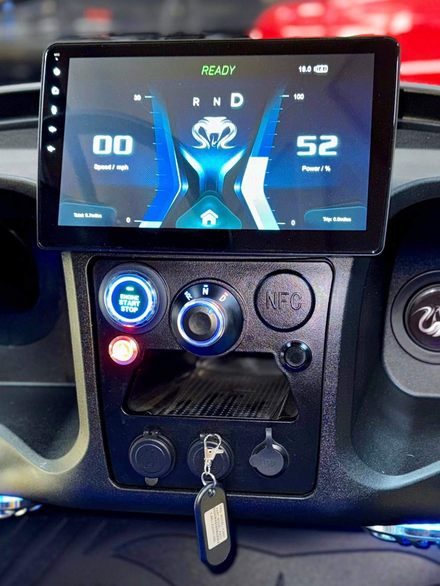 Dashboard with digital display showing speed, gear, and power. Black controls and a key.