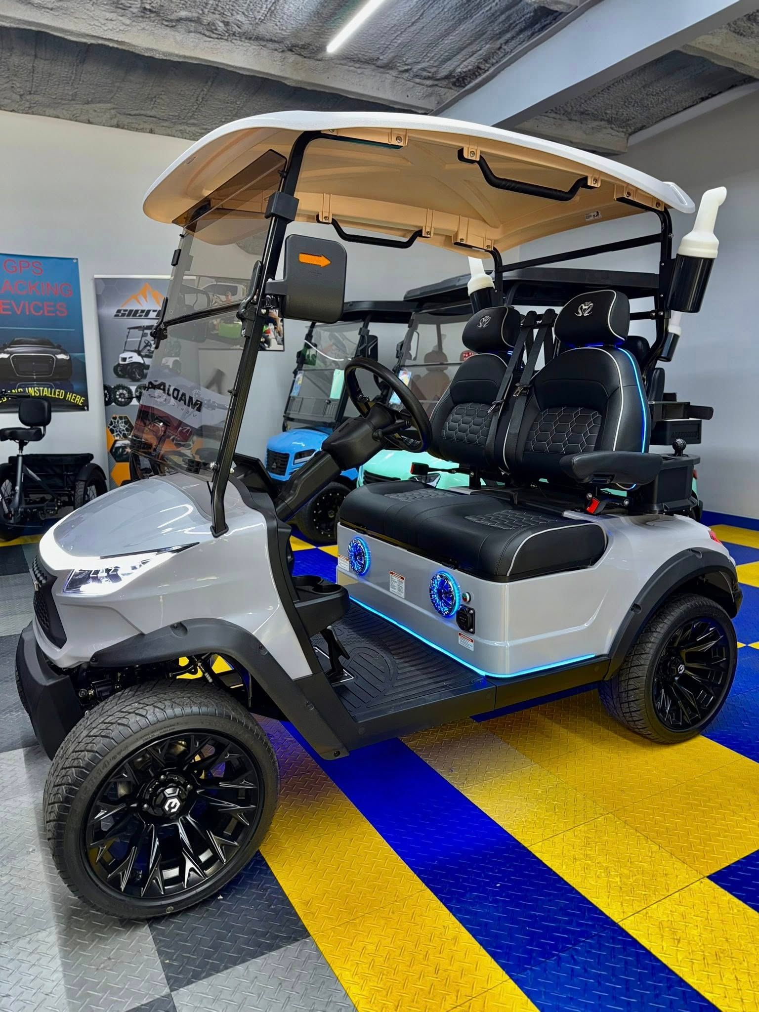 Gray and black golf cart with black wheels, on blue and yellow checkered floor.