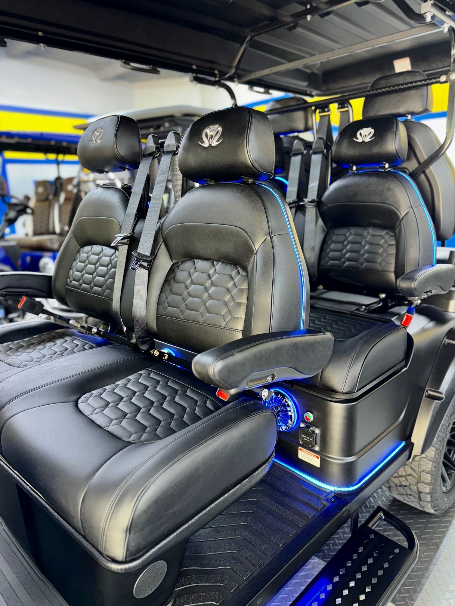 Black golf cart interior with quilted black leather seats, armrests, and blue LED lighting.