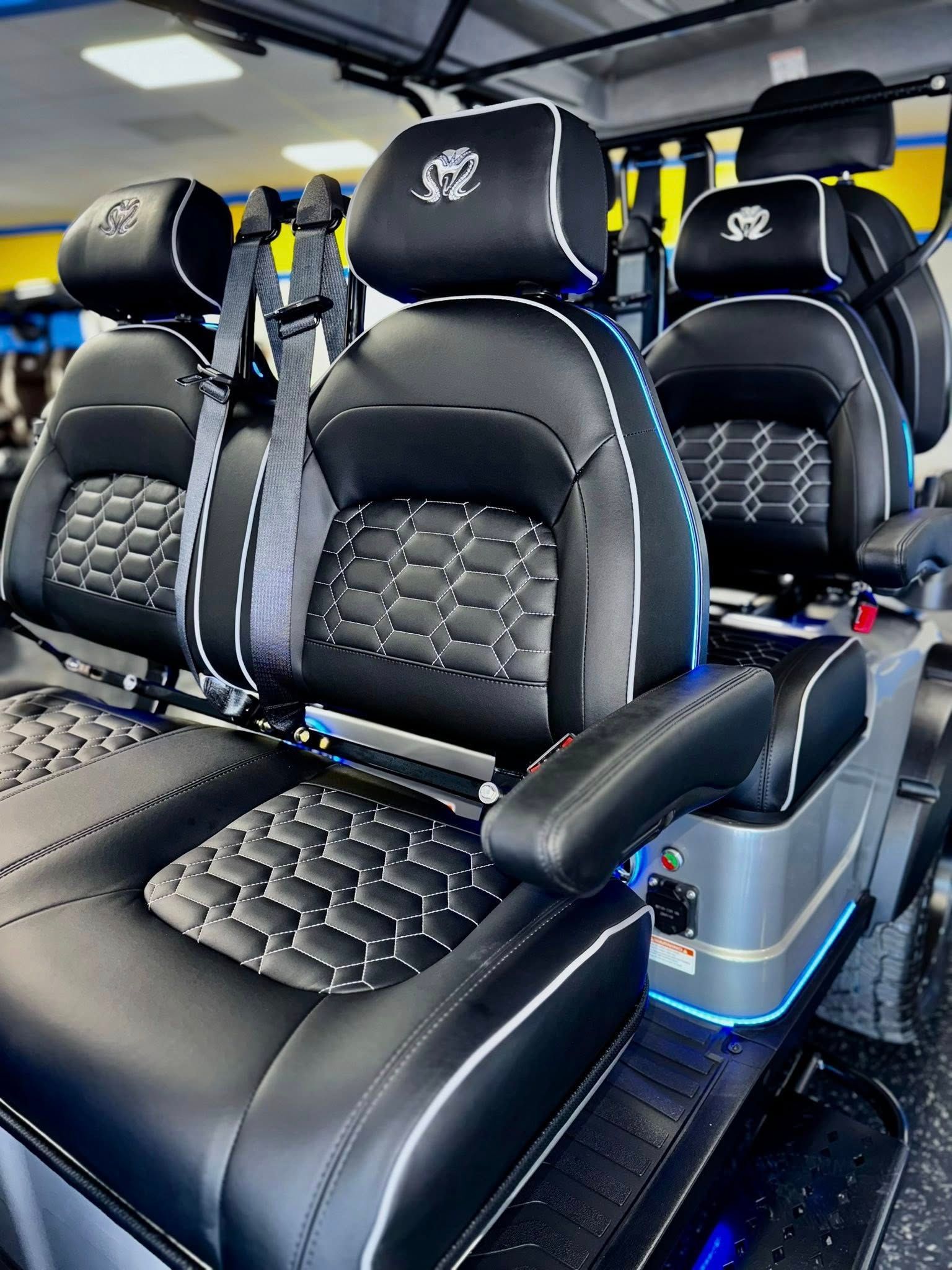 Custom golf cart interior with black leather seats, white trim, and a blue ambient glow.