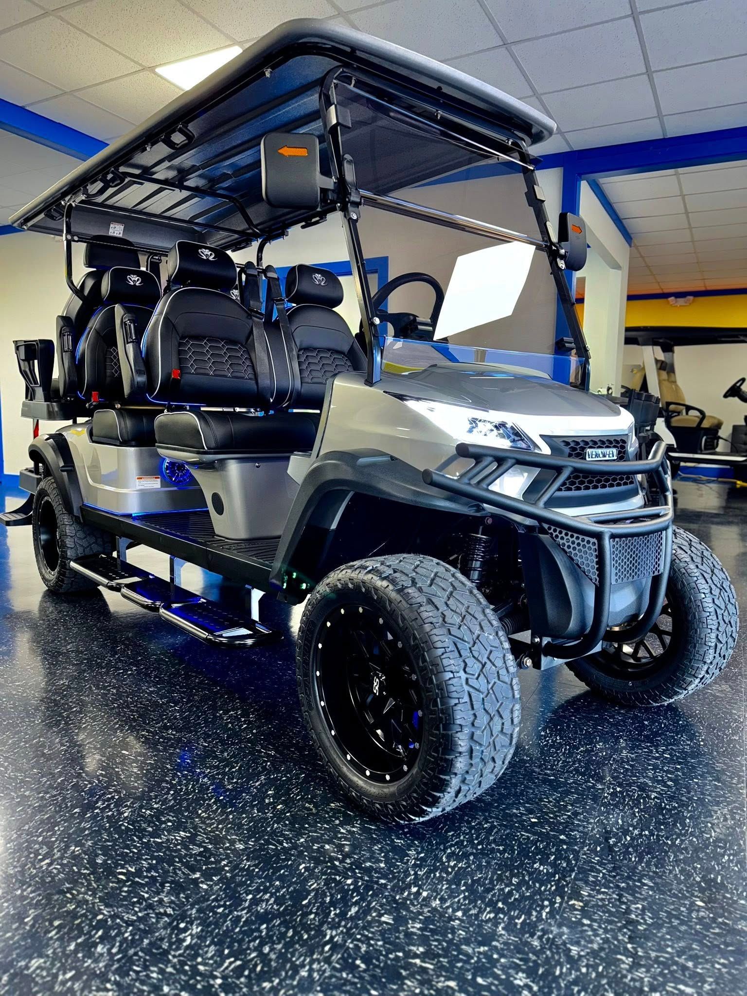 Gray and black golf cart with rugged tires, parked indoors with blue and white accents.
