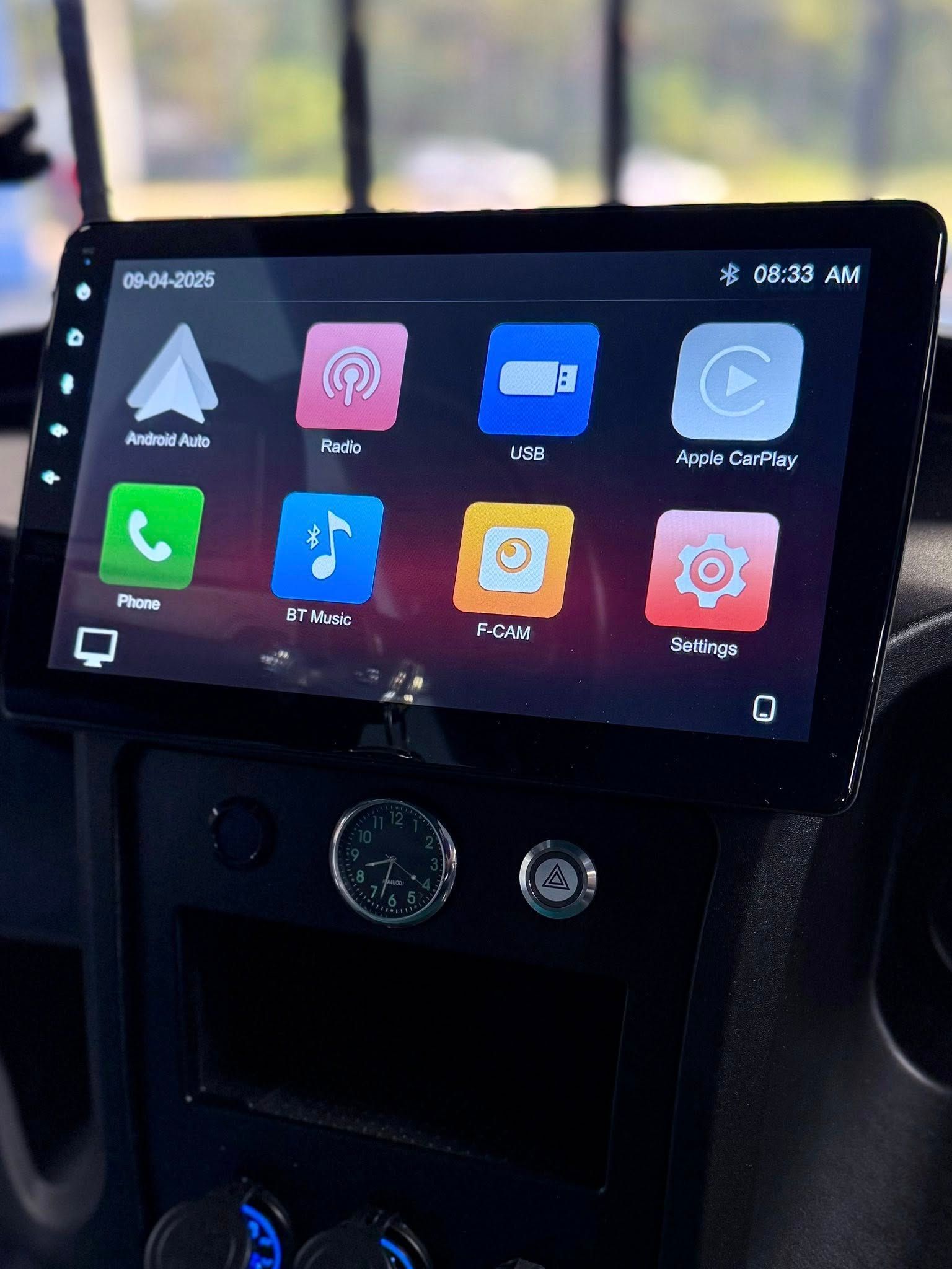 Car's touchscreen display showing app icons: Android Auto, Phone, Maps, Apple CarPlay, and Settings.