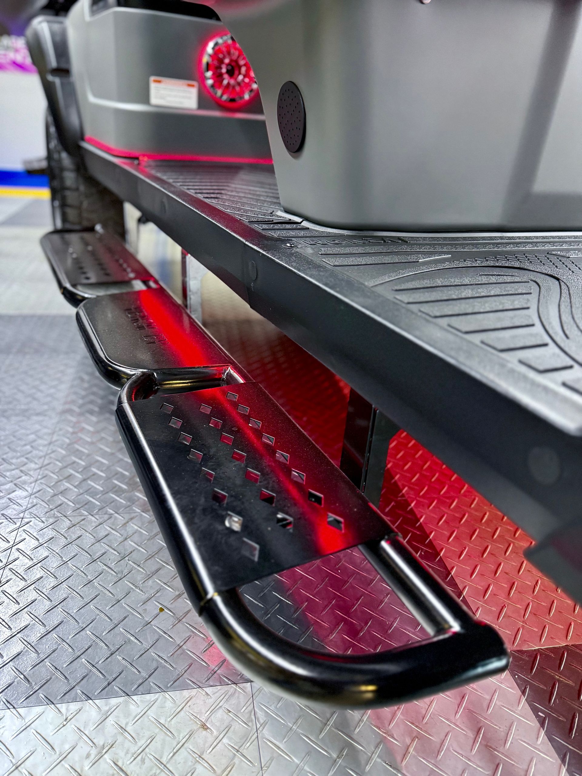 Black running board on a vehicle, showing steps and an underneath red glow.