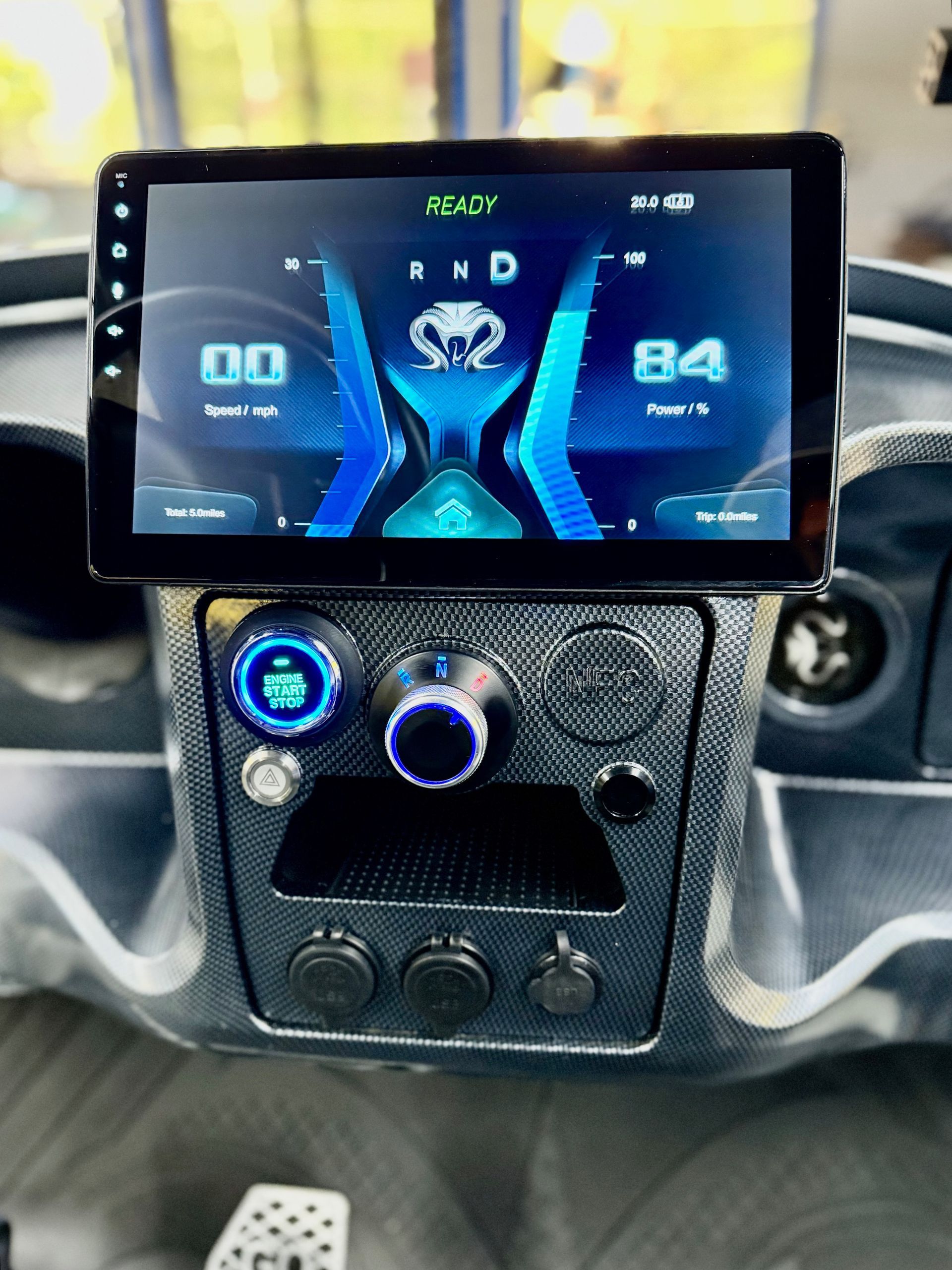 Dashboard with digital display showing speed and gear. Blue accents, black console.