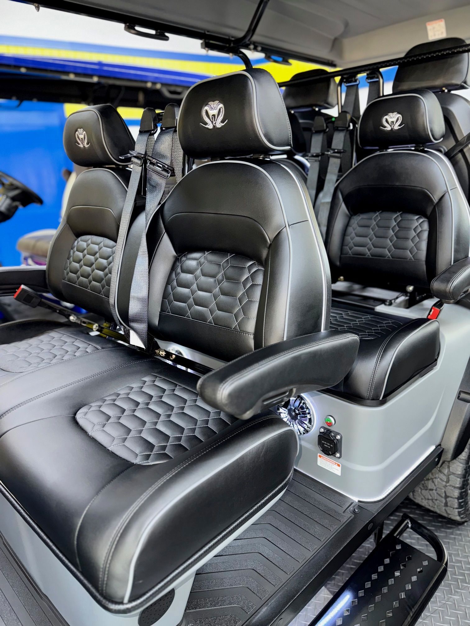Black leather seats in a gray golf cart with white stitching and armrests; the seats have headrests.