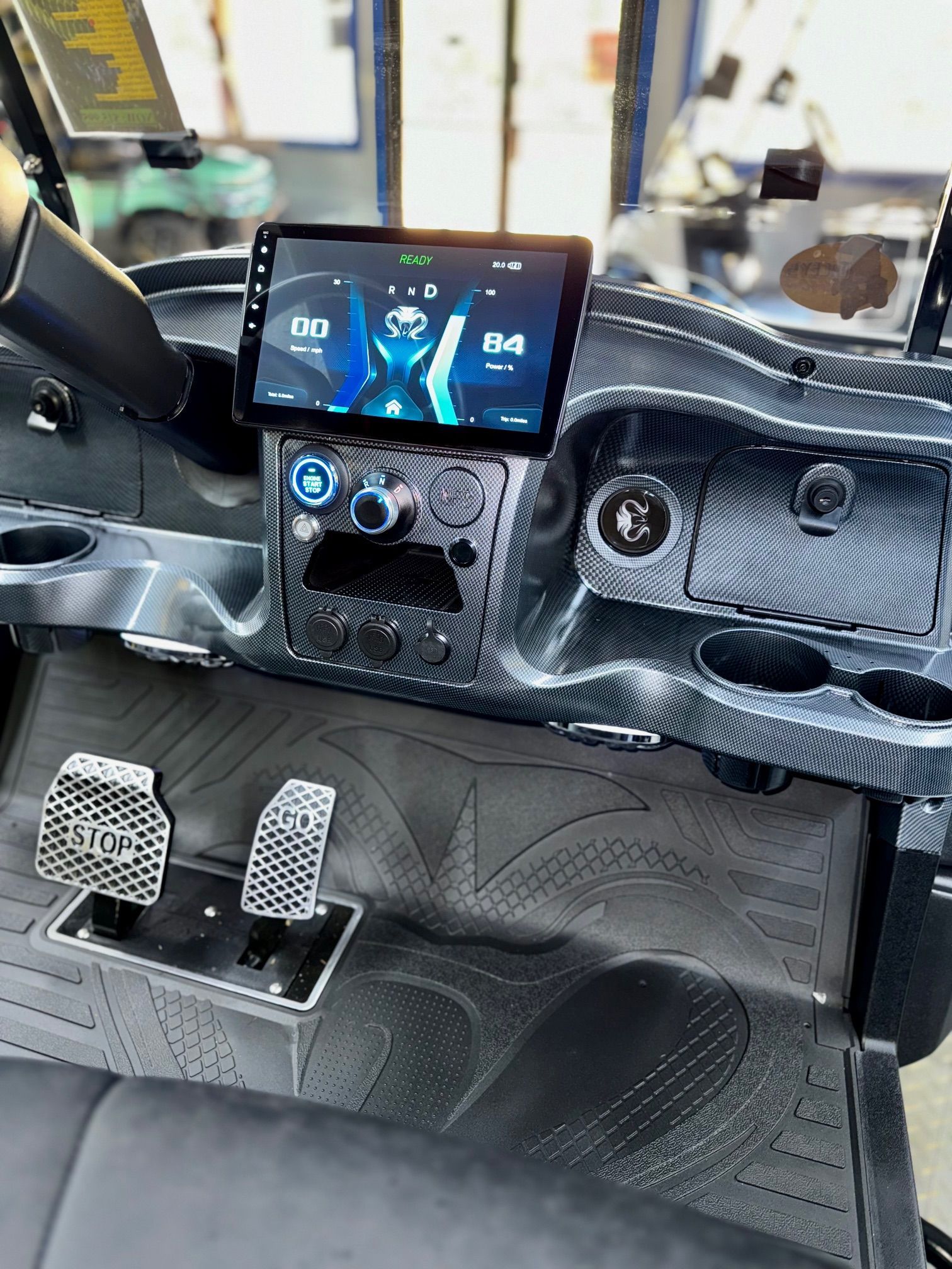 Golf cart dashboard with a large touchscreen display, cup holders, and custom pedals.