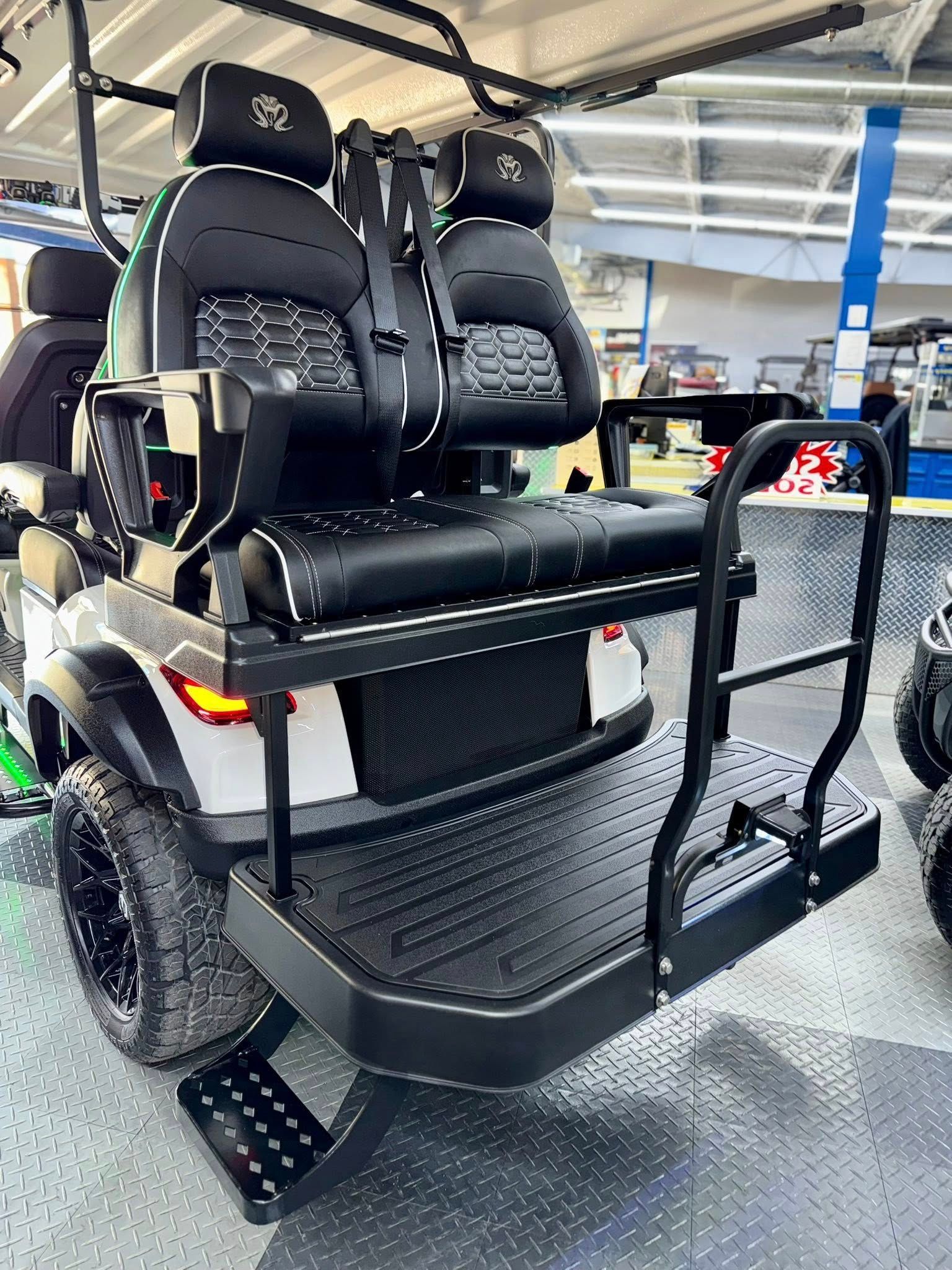 White golf cart with black seating, rear bench, and custom wheels.