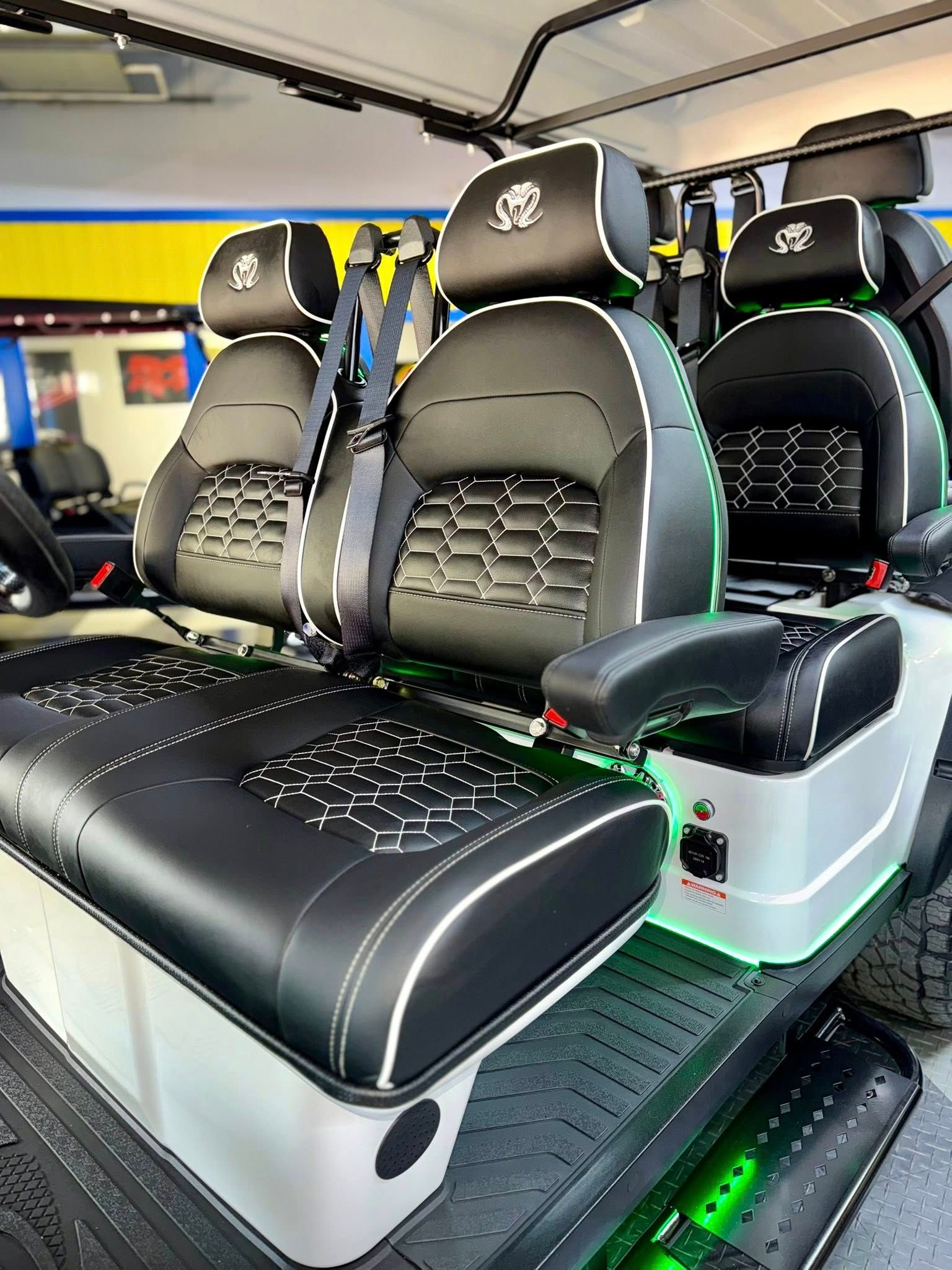 Custom black golf cart seats with white stitching and green lights.