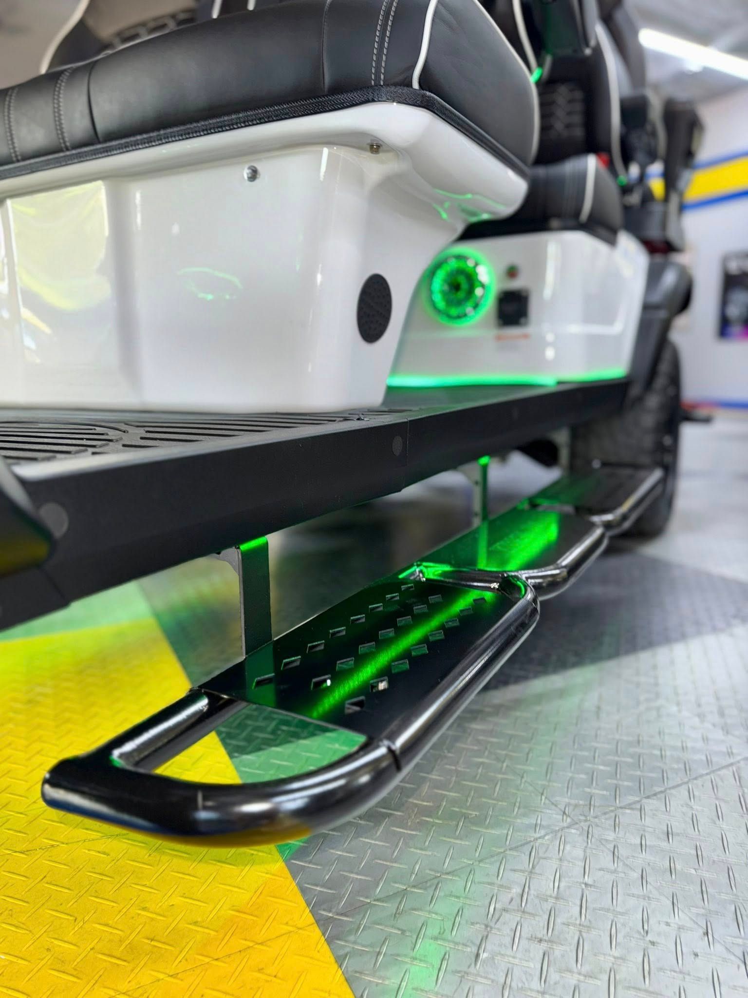 White golf cart with black accents and green underglow; step-up bar.