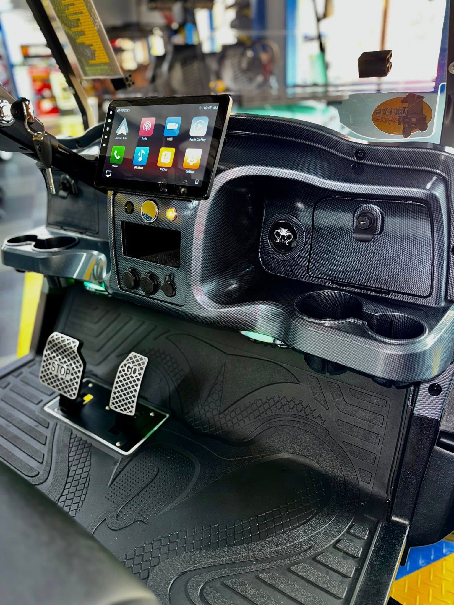 Customized golf cart interior with touch screen display and textured dashboard.
