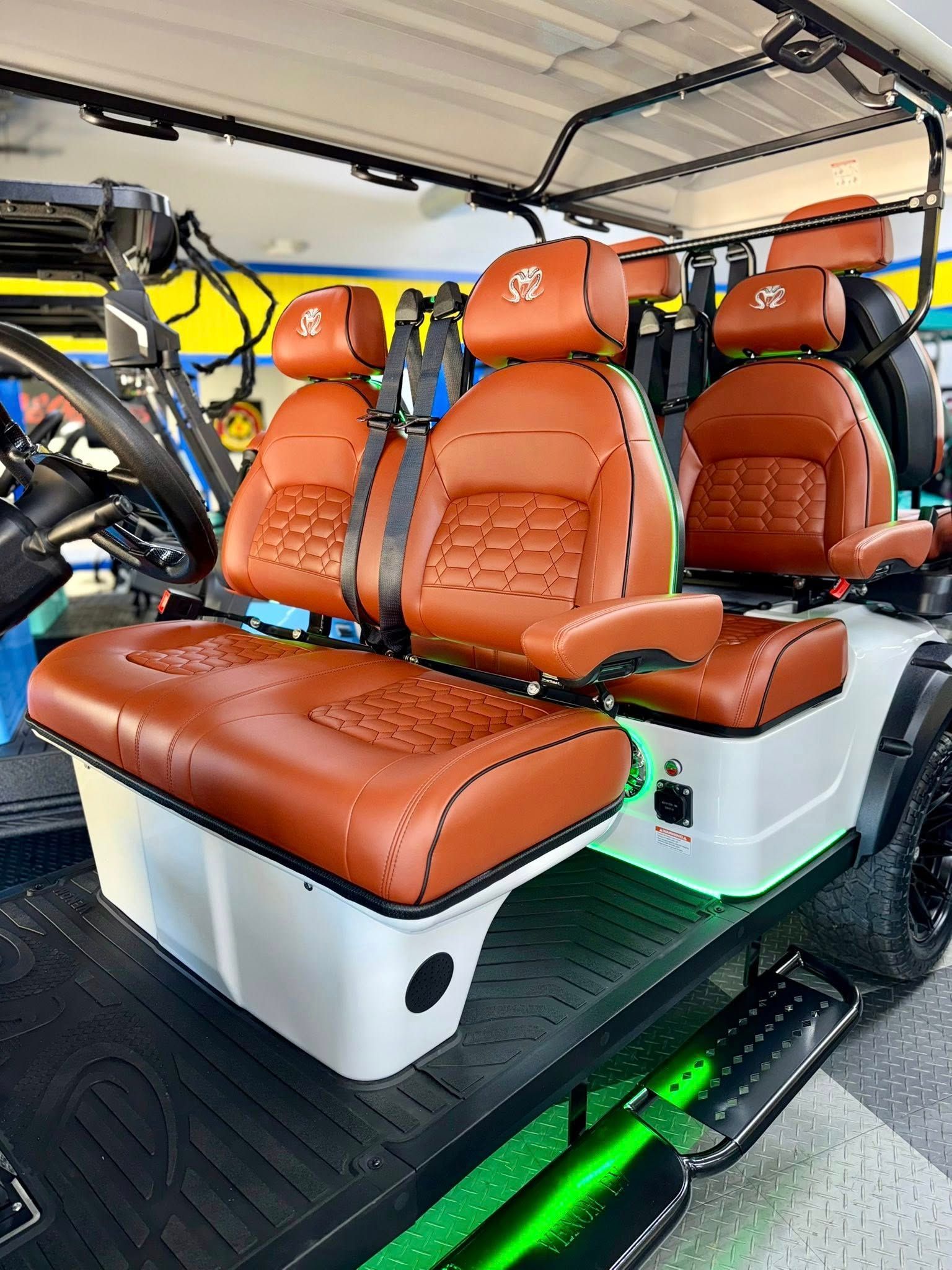 Brown and white custom golf cart with leather seats and green underglow.
