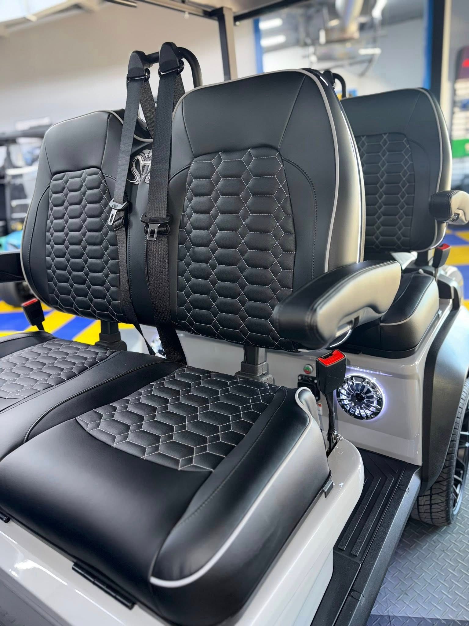 Gray golf cart seats with black upholstery and safety straps.