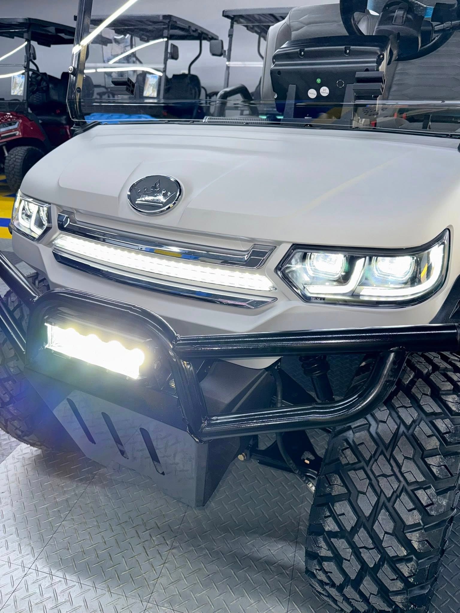 White golf cart with LED light bars and rugged tires.