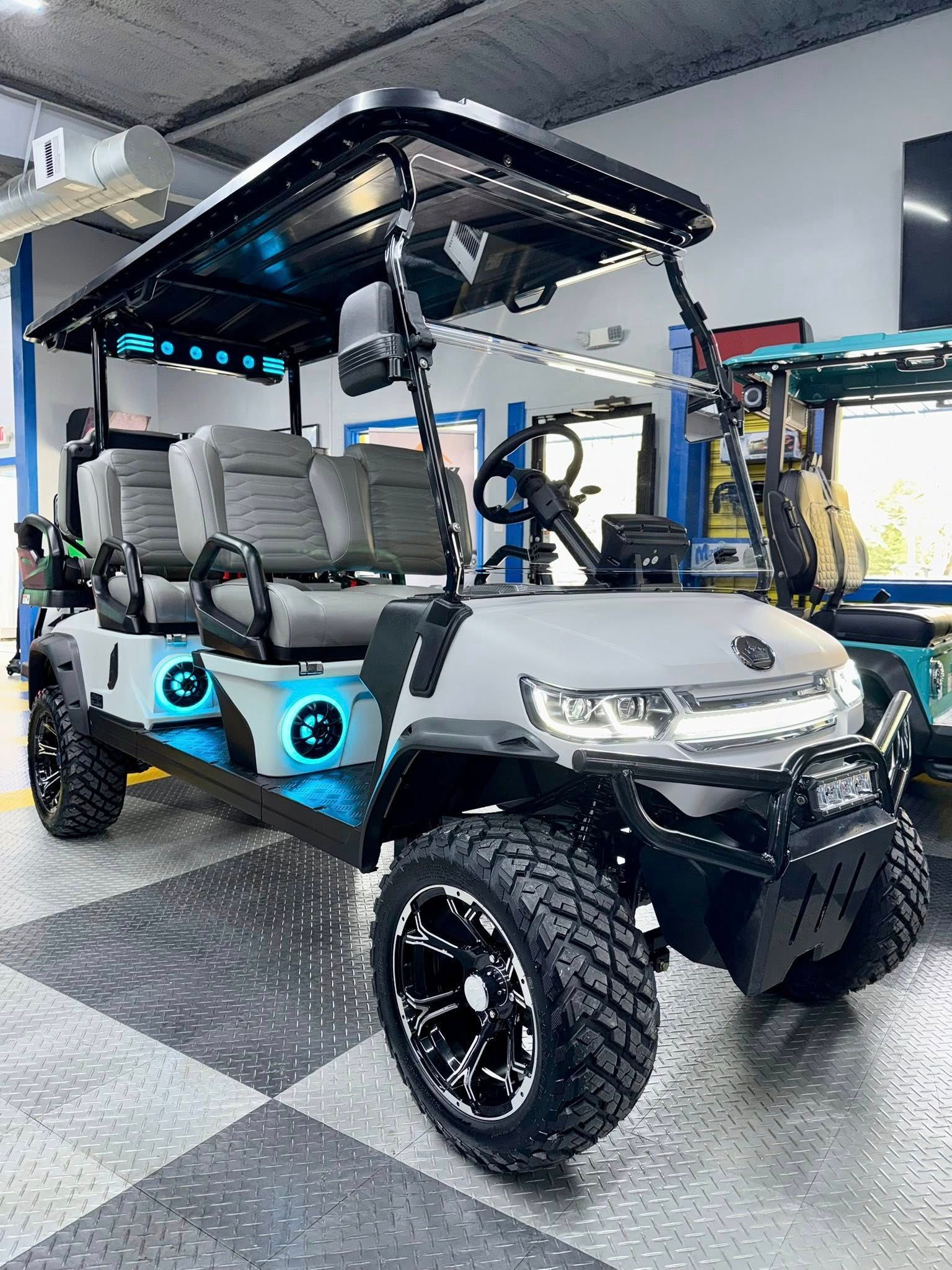 Grey and black lifted golf cart with off-road tires, blue accents, and a black roof.