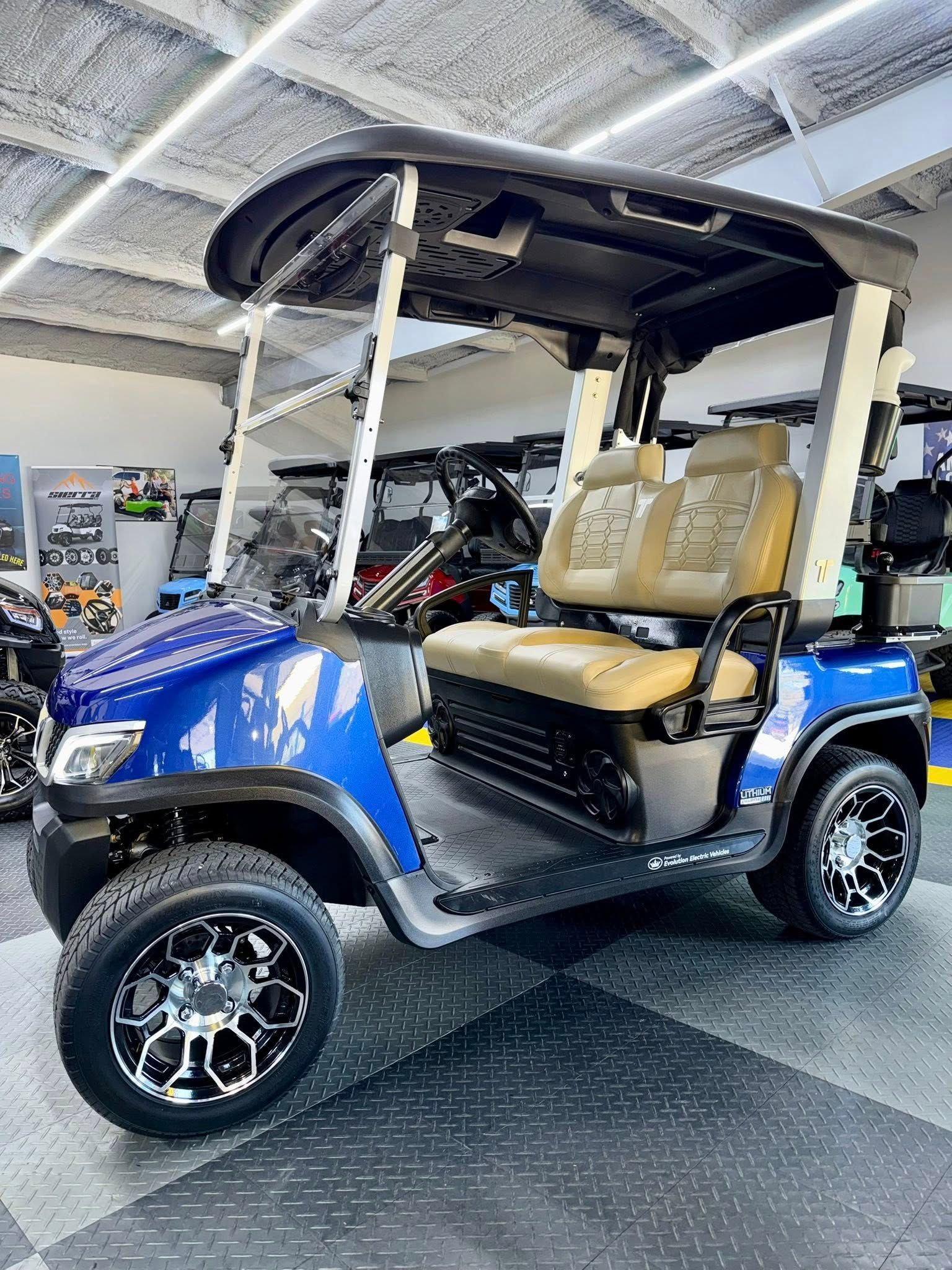 Blue golf cart with black roof and wheels, tan seats, inside a showroom.
