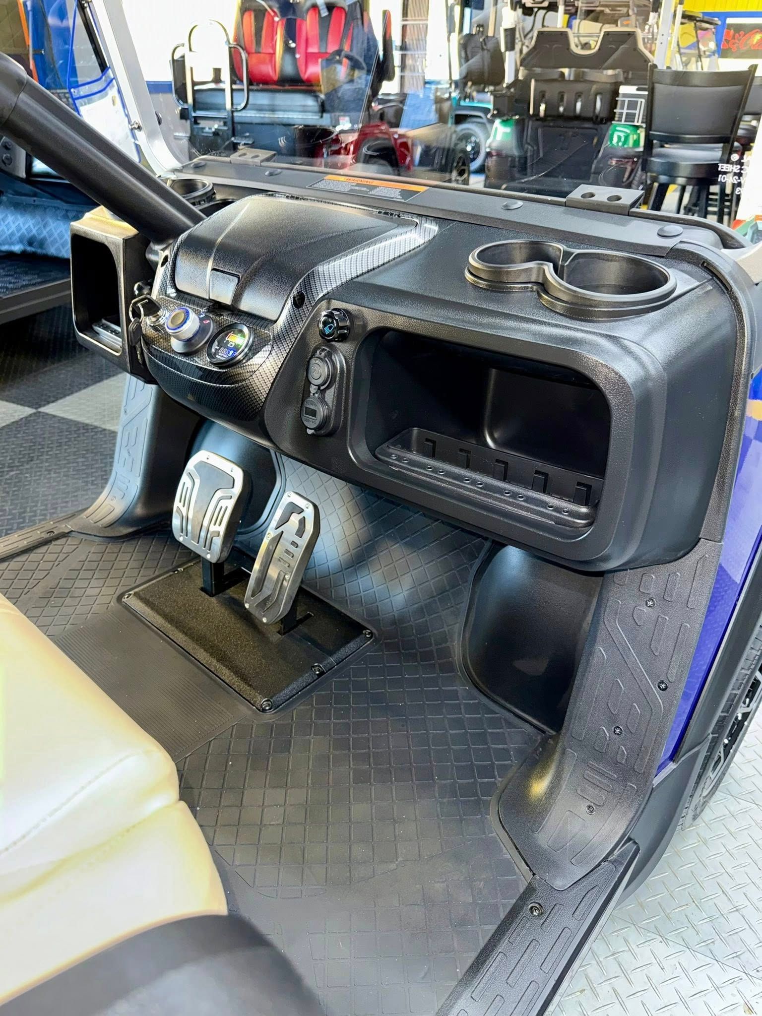 Golf cart dashboard with cup holders, storage, and pedals.