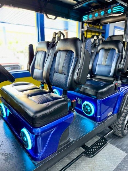 A blue golf cart with black seats and blue lights