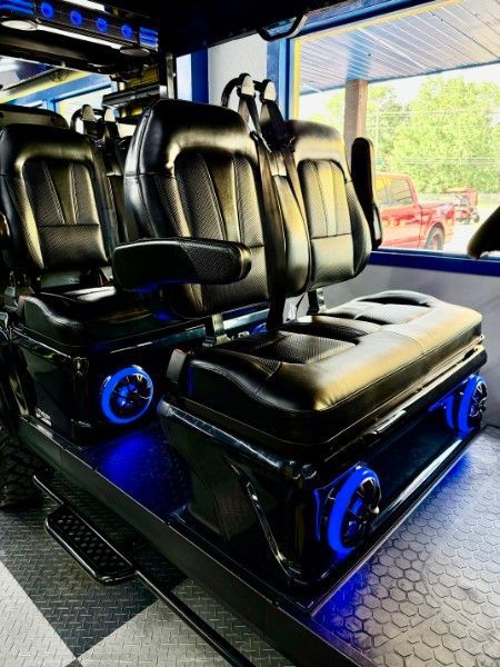A row of black seats in a car with blue lights