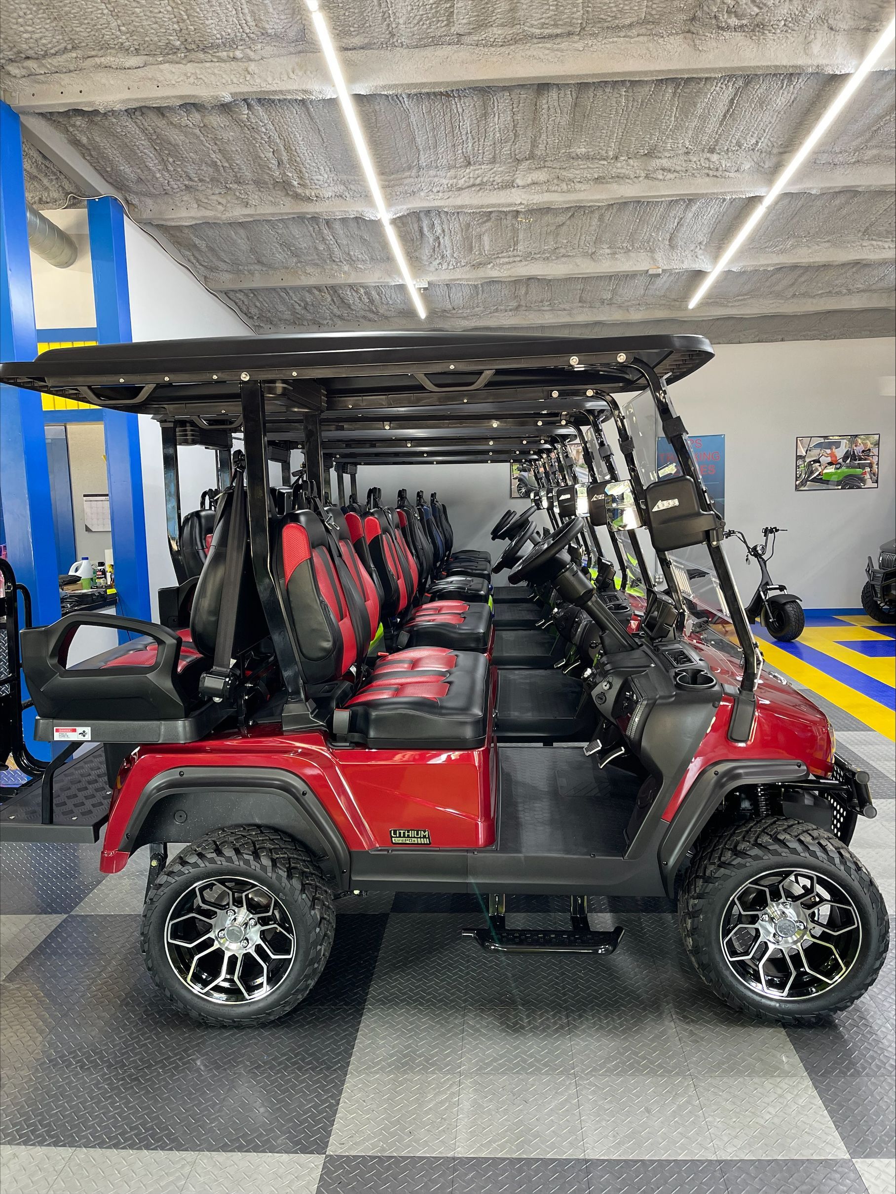 Red golf carts with black accents and red seats lined up in a showroom, showcasing their features.