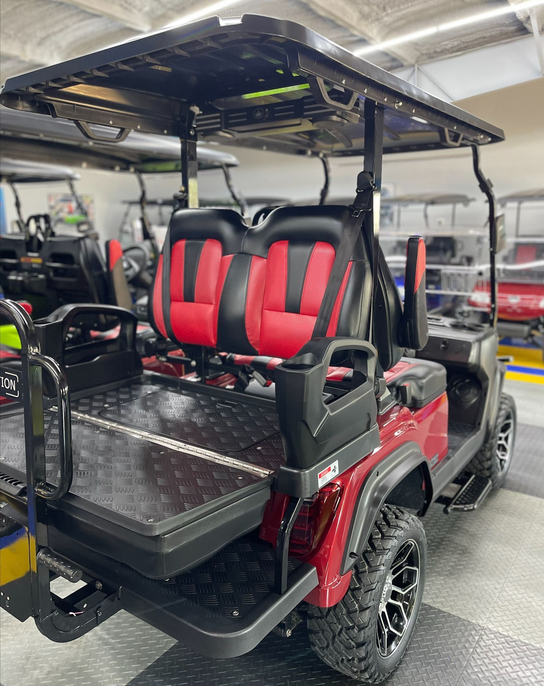 A red golf cart with red seats is parked in a garage.