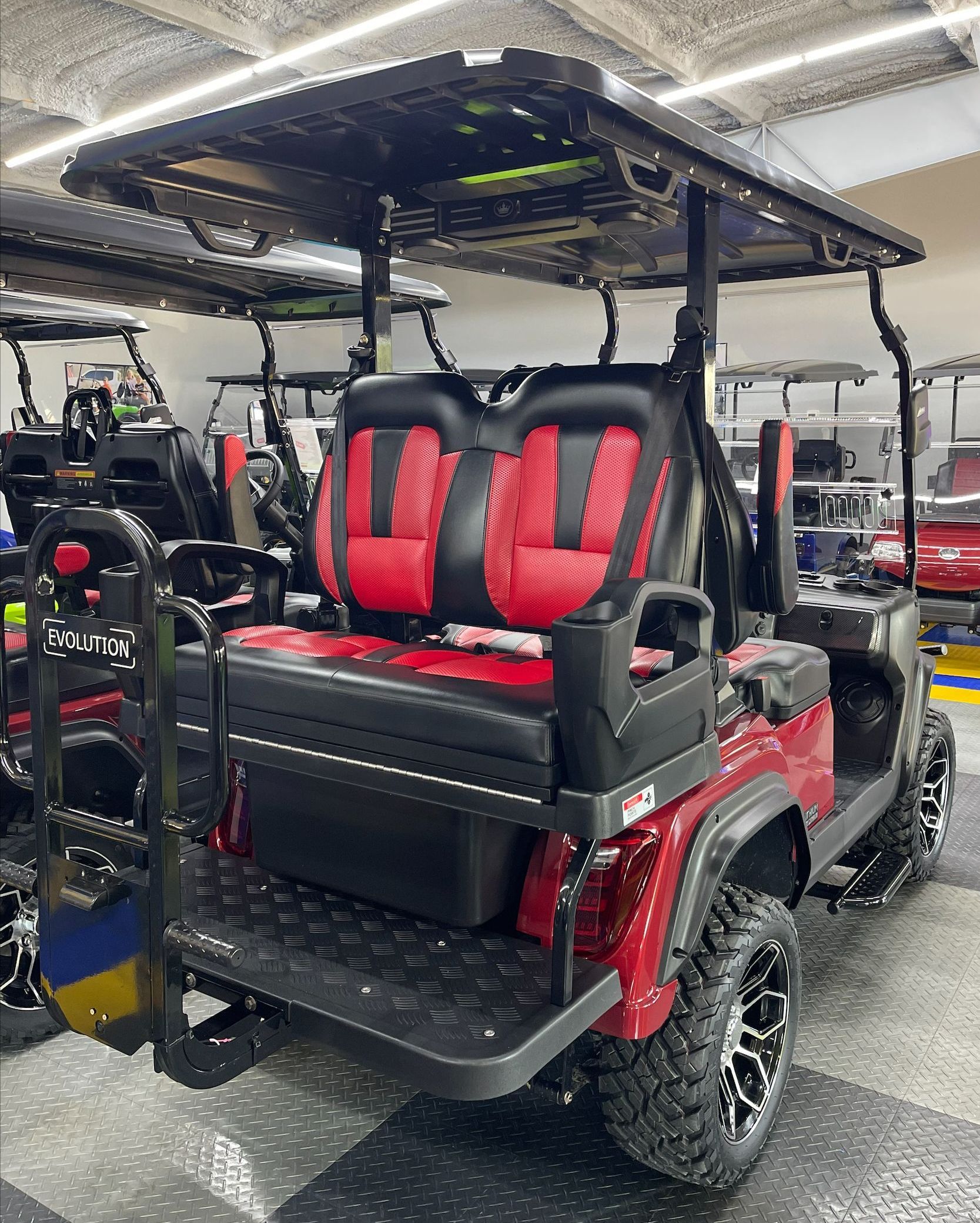 A red golf cart with red seats is parked in a garage.