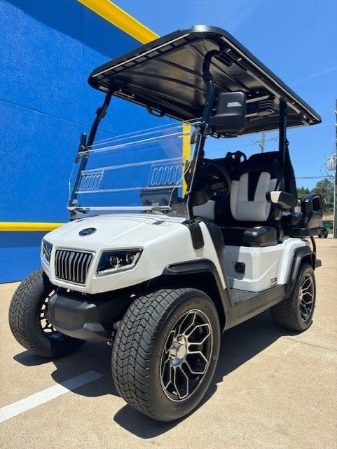 A white golf cart is parked in front of a blue building