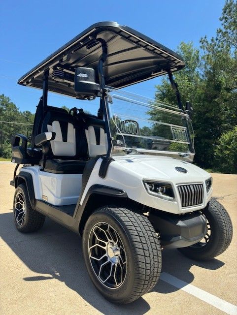 A white golf cart is parked in a parking lot