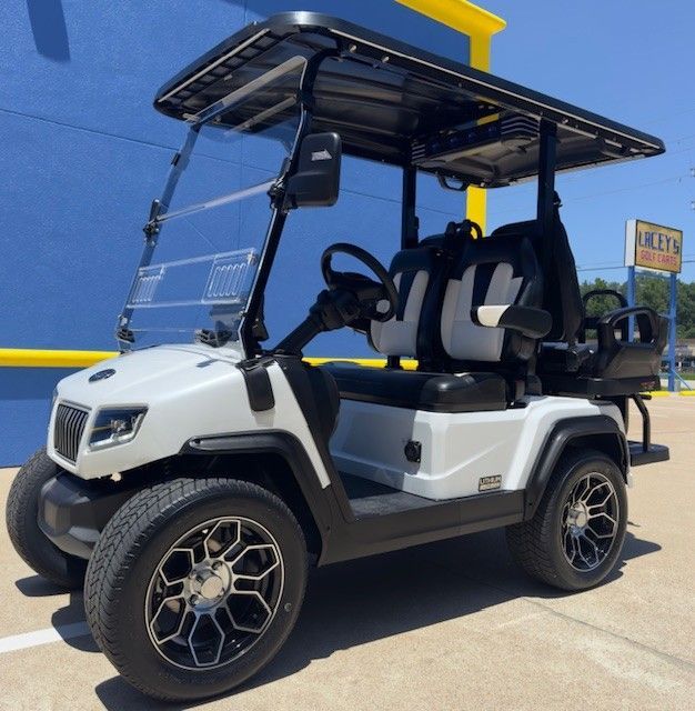 A white golf cart is parked in front of a blue building