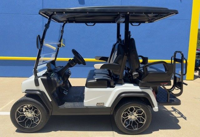 A white golf cart is parked in front of a blue building
