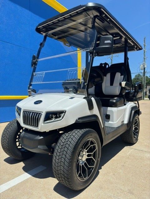 A white golf cart is parked in front of a blue building