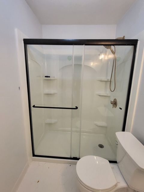 A bathroom with a toilet and shower with sliding glass doors