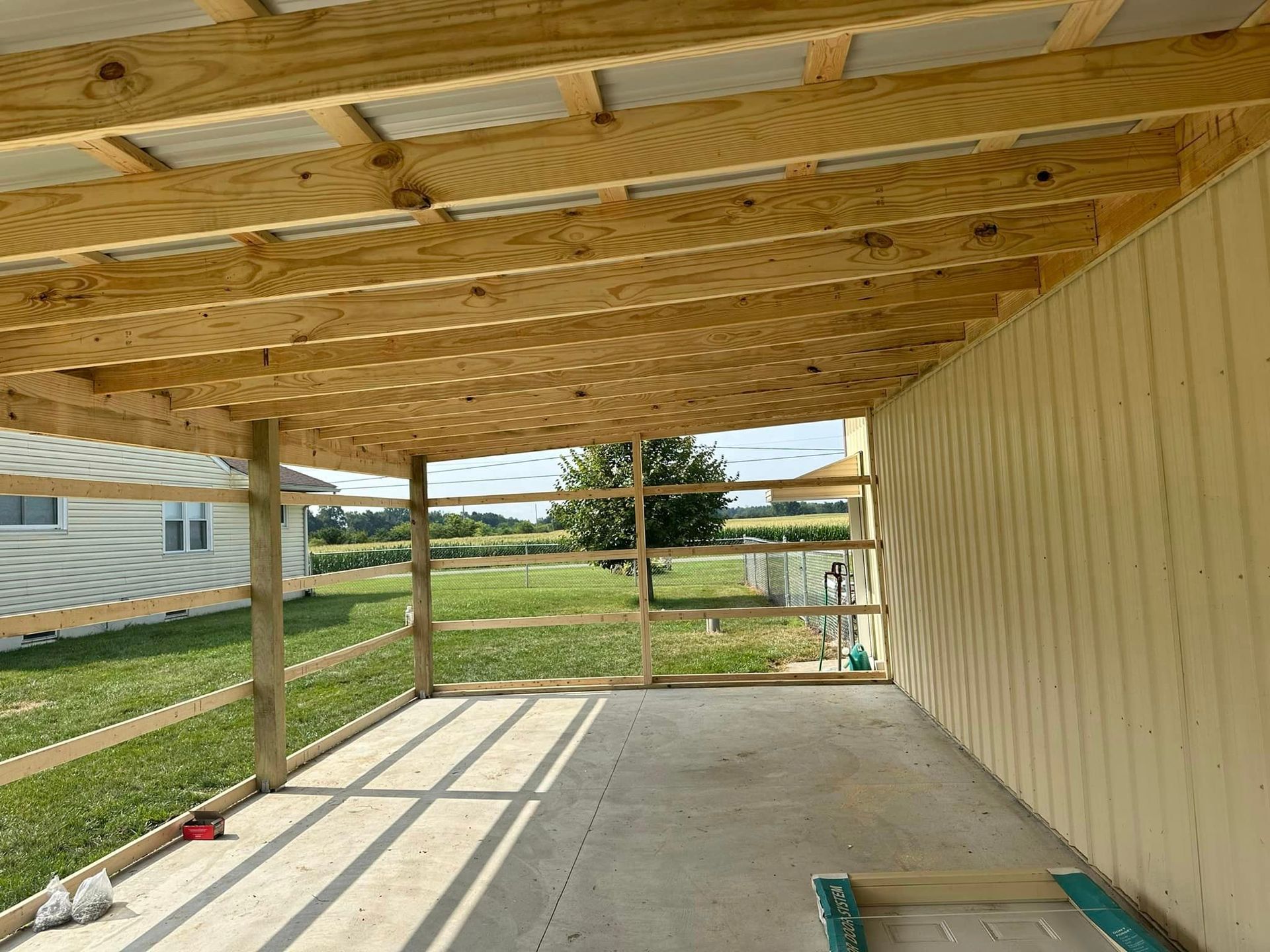 A carport with a wooden roof is being built in front of a house.