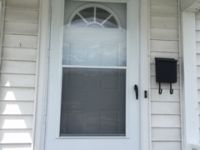 A white door with a screen and a mailbox on the side of a house.