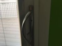A close up of a door handle on a window with blinds.