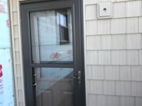 A black door with a glass window is on the side of a house.