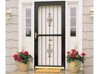 A black door with a wrought iron gate is sitting on a porch next to potted flowers.