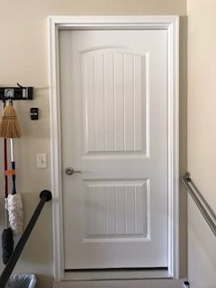 A white door is hanging on a wall next to a staircase.